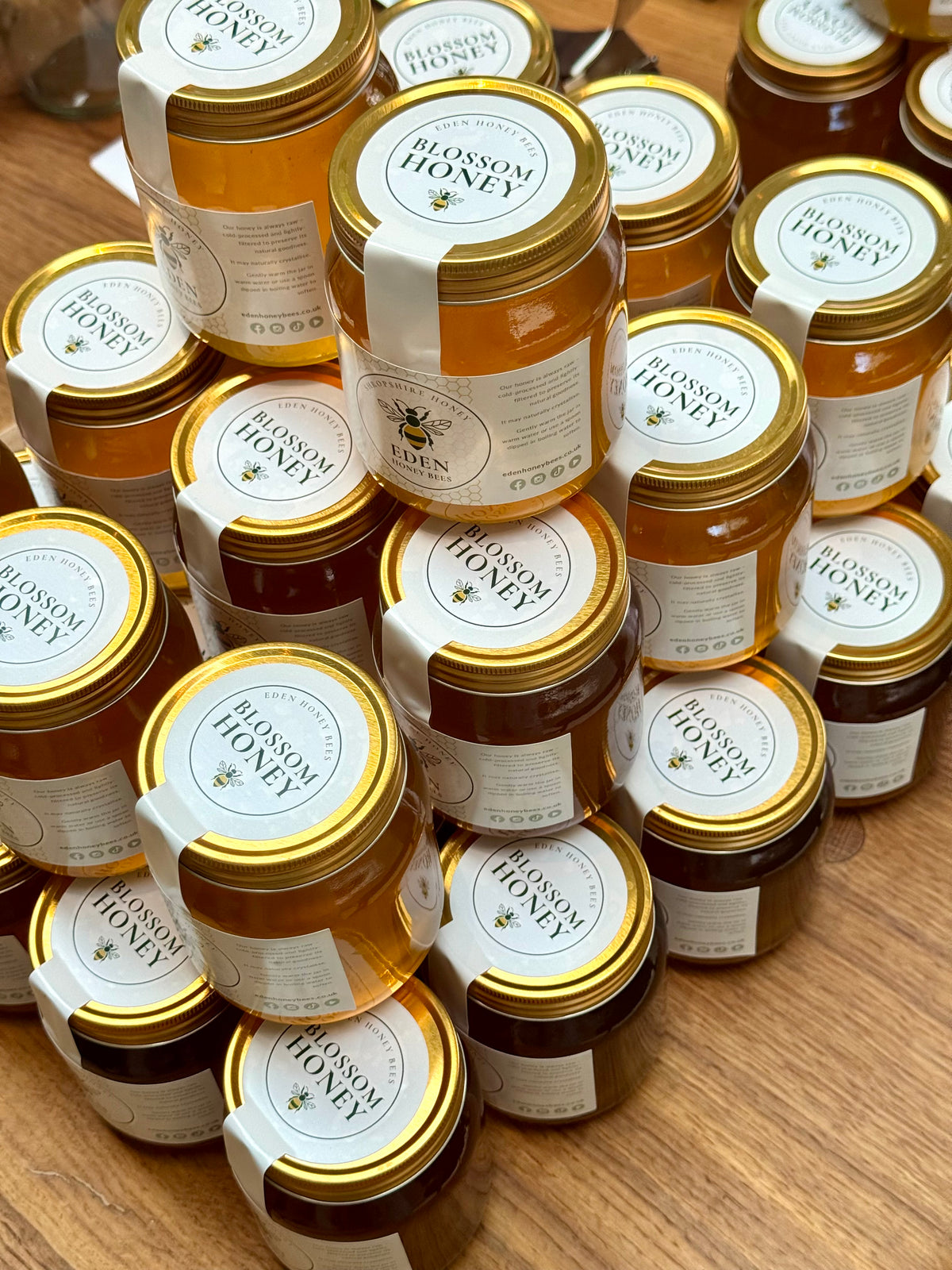 Multiple jars of Blossom Honey stacked on a wooden surface